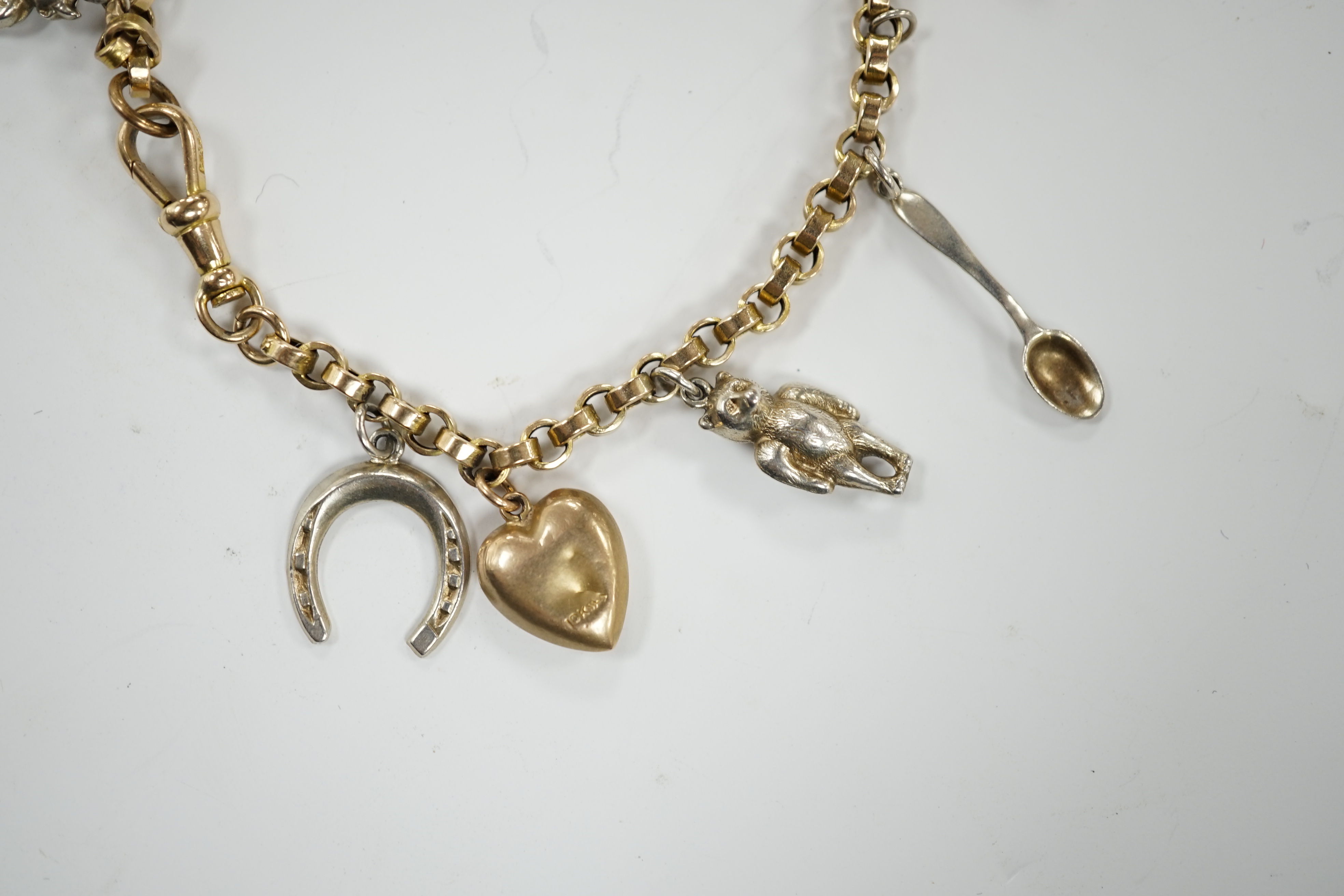 A 9ct charm bracelet, hung with nine assorted yellow and white metal charms including sterling and 10k, 16cm